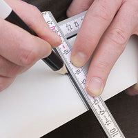 Hands holding a ruler and marking a line on an object with a black Pica pencil