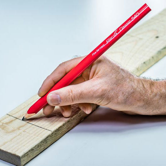 Hand marking a line on a piece of wood using a Pica Classic 540 Carpenter Pencil